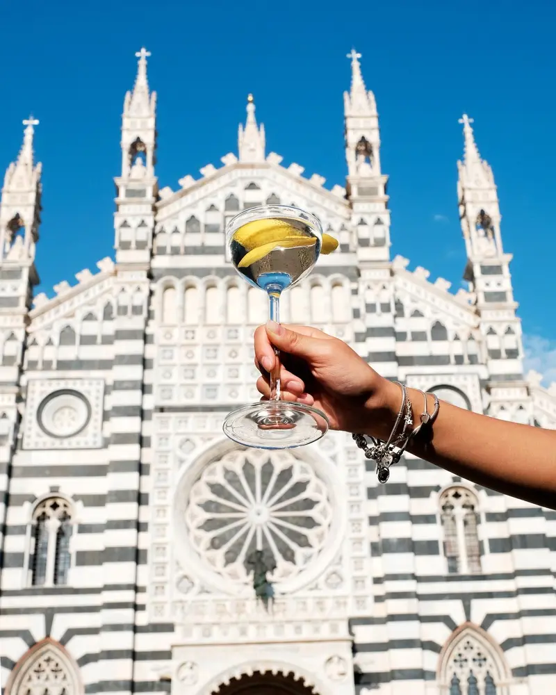 Una coppa alzata davanti alla facciata del Duomo, cielo blu.