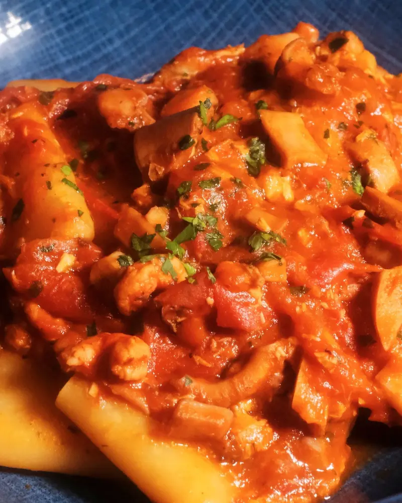 Paccheri al ragù di mare su un piatto blu.